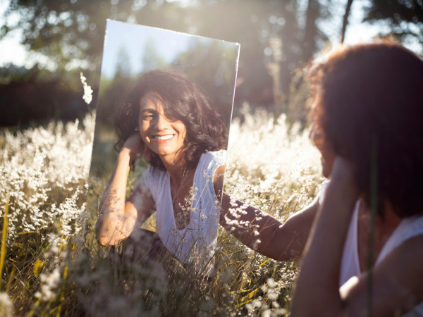 Frau lächelt im Spiegel: Erfolge in der Therapie von Schamgefühlen
